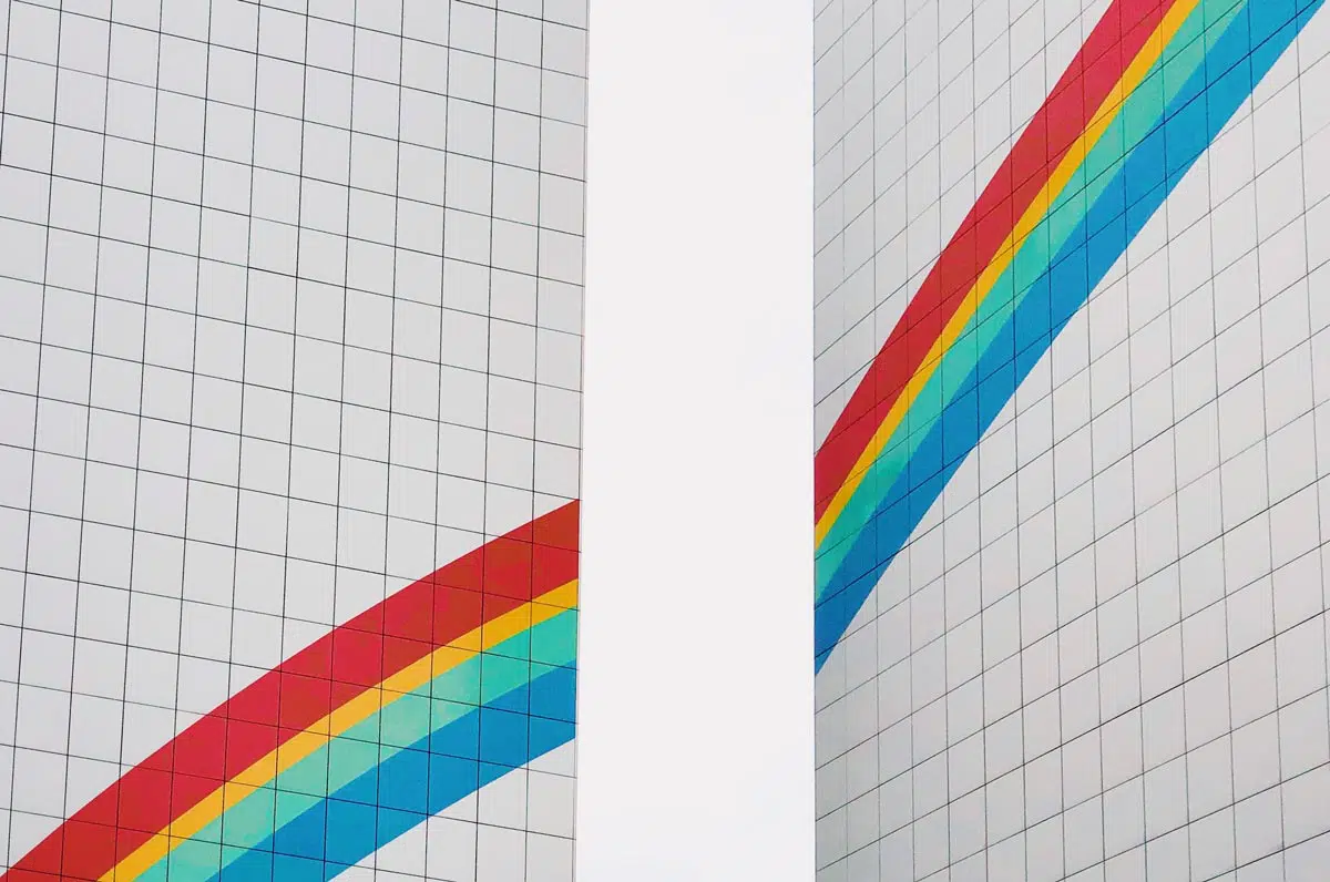 Two building façades with rainbow painted on.